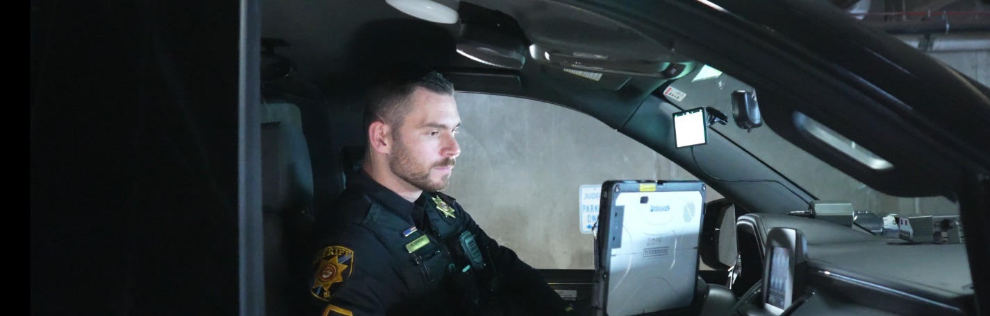 Deputy Sheriff Working on MDT in Patrol Car with Emergency Lights On
